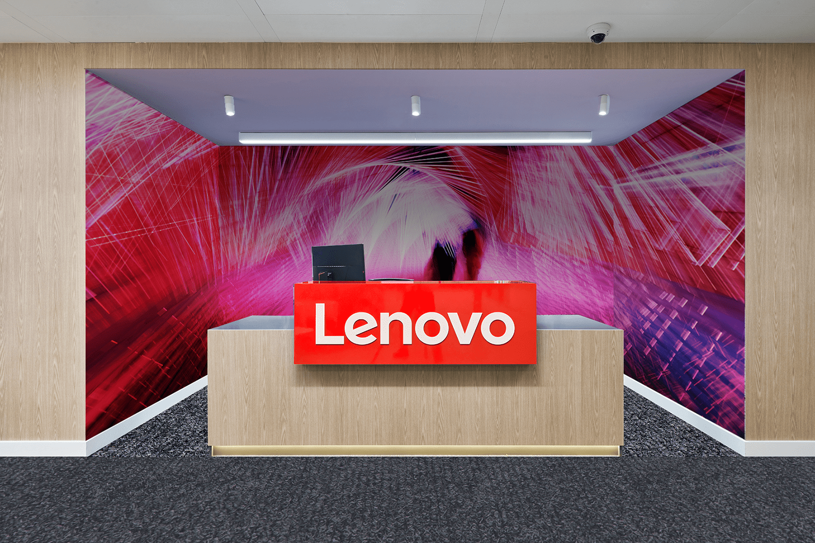 A reception desk with a Lenovo logo and an abstract red and purple background.